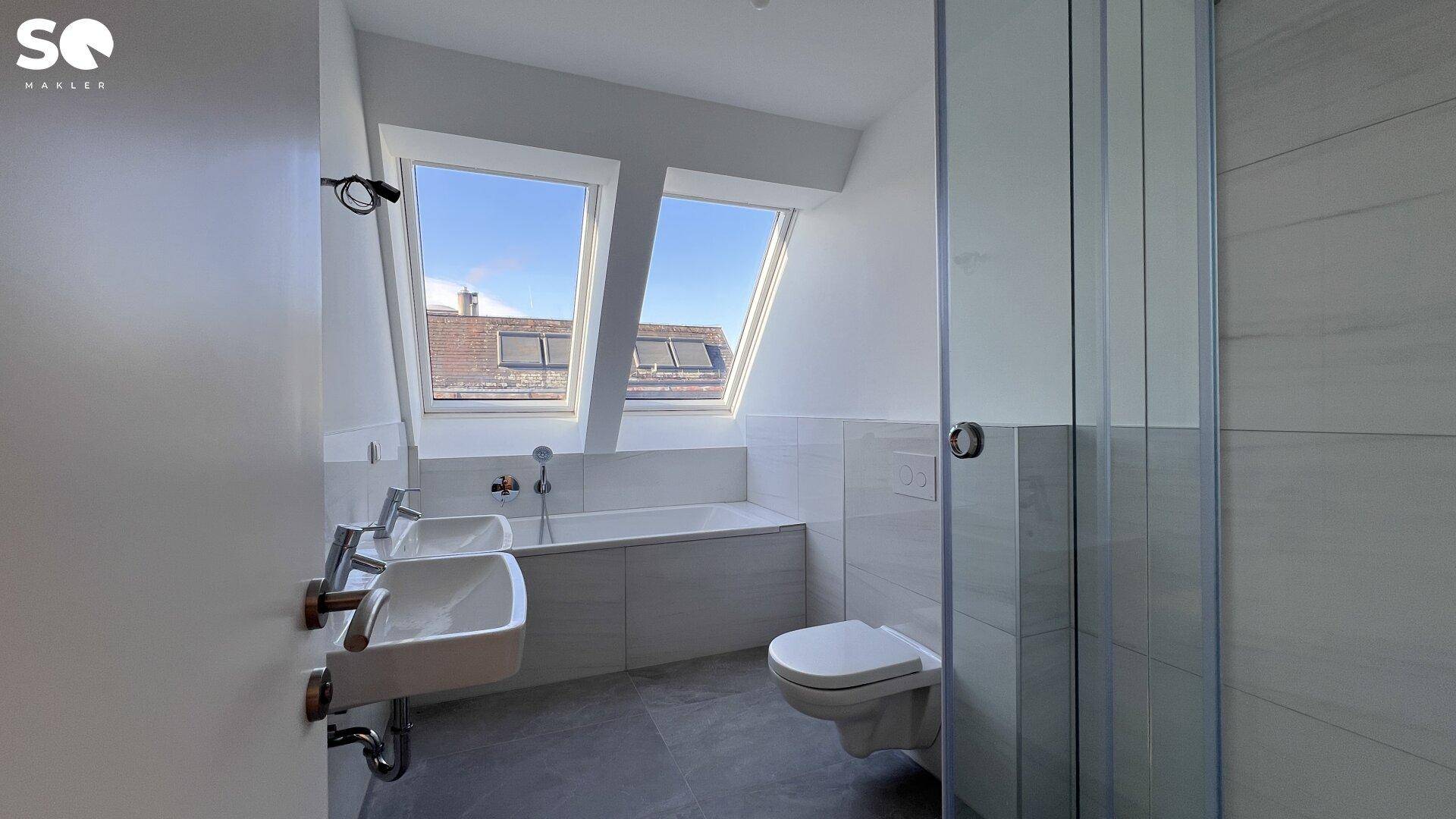 Modernes Badezimmer mit Doppelwaschbecken, Badewanne und Dachfenstern für viel Licht.
