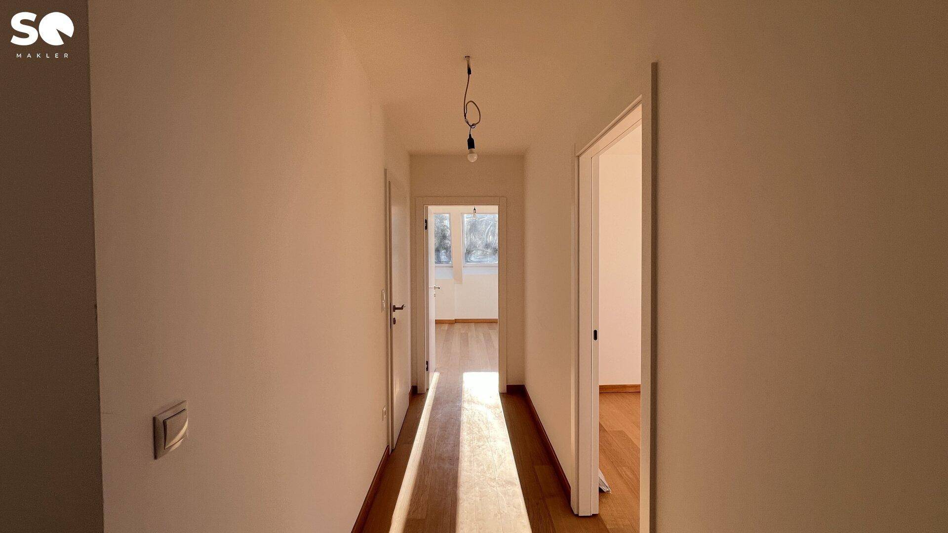 Langer, heller Flur mit Holzboden, der zu verschiedenen Zimmern im Dachgeschoss führt.