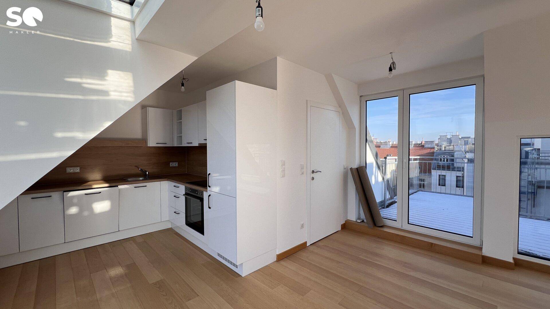 Moderne Einbauküche mit weißen Fronten, Holzarbeitsplatte und direktem Zugang zur Terrasse.
