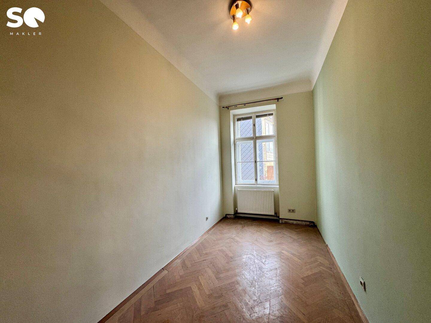 Kleinerer Raum mit Fischgrätparkett und hellgrünen Wänden, ideal als Kinderzimmer.