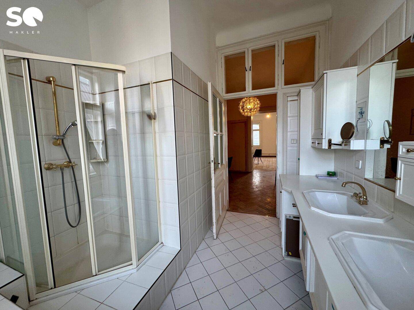 Badezimmer mit Duschkabine, Fliesenboden und Zugang zu einem weiteren Raum.