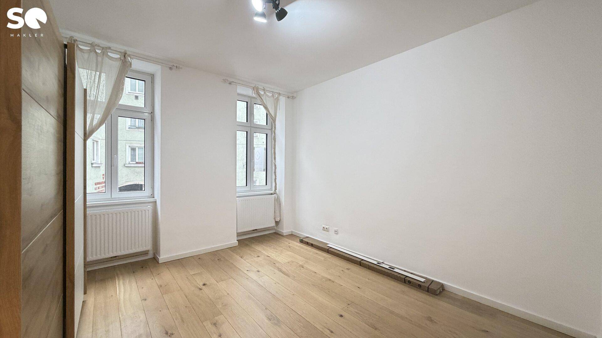Schlafzimmer mit Parkettboden, zwei Fenstern und viel Tageslicht, bereit zur individuellen Gestaltung.