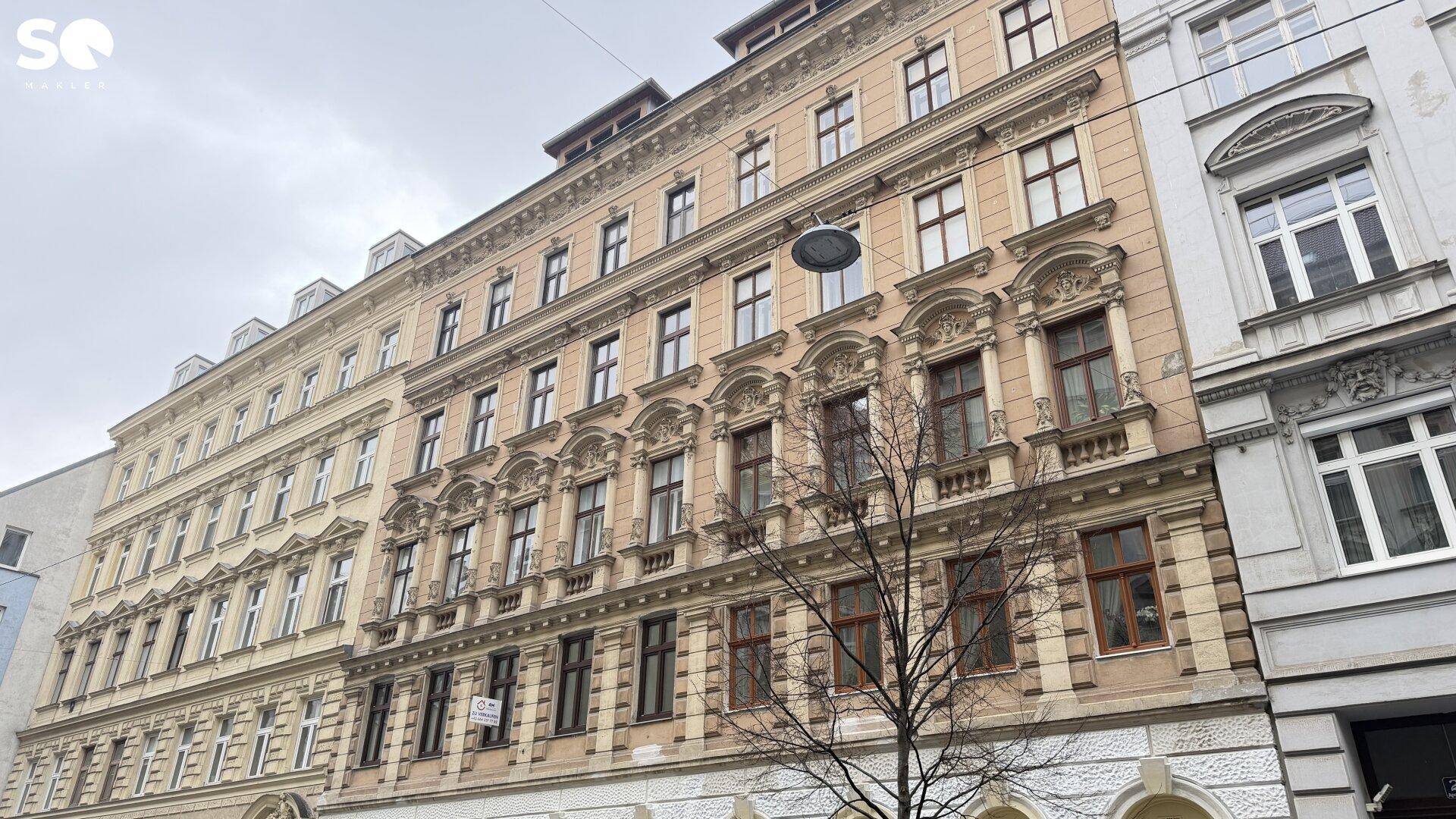 Historisches Wohngebäude mit reich verzierter Fassade und vielen Fenstern in urbaner Umgebung.