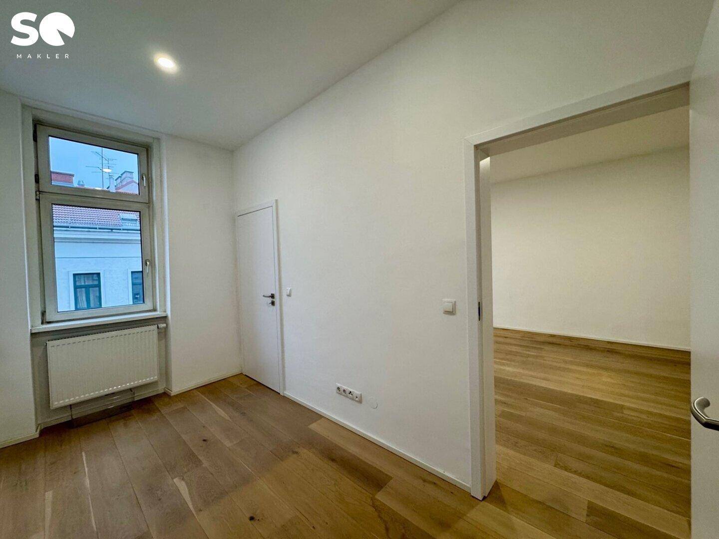 Kleineres Zimmer mit Holzboden und einem Fenster, ideal als Schlaf- oder Arbeitszimmer.
