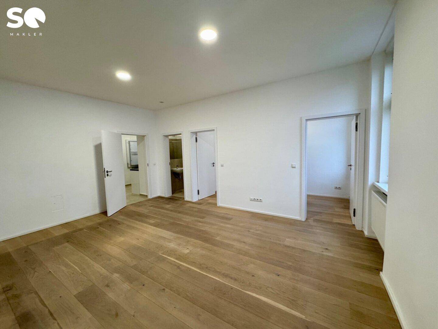 Heller Flur mit Holzboden und mehreren Türen, der Zugang zu verschiedenen Räumen bietet.