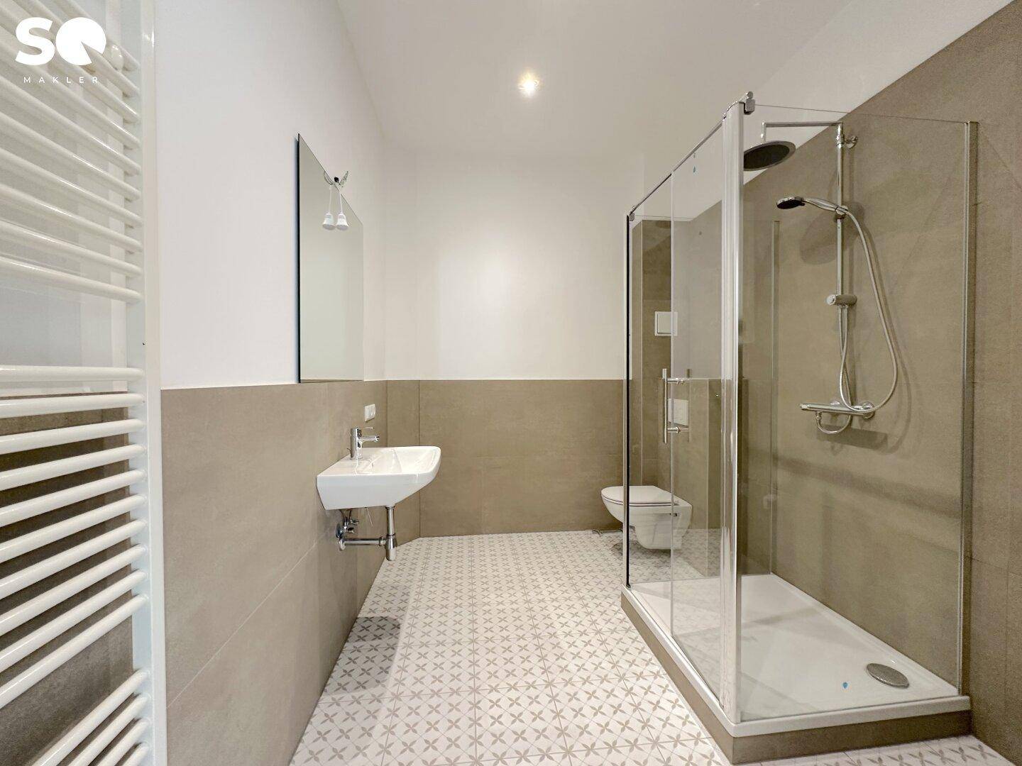 Modernes Badezimmer mit begehbarer Dusche, eleganten Fliesen und einem Wand-WC, ausgestattet mit Handtuchheizkörper.