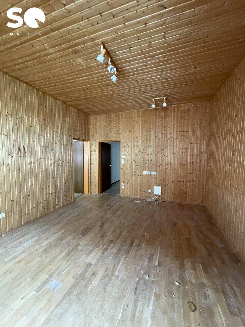 Geräumiges Zimmer mit Holzvertäfelung an Wänden und Decke sowie Parkettboden.