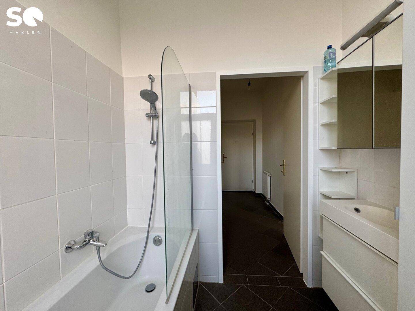 Badezimmer mit Badewanne und Duschvorrichtung, sowie einem Waschbecken mit Spiegelschrank.