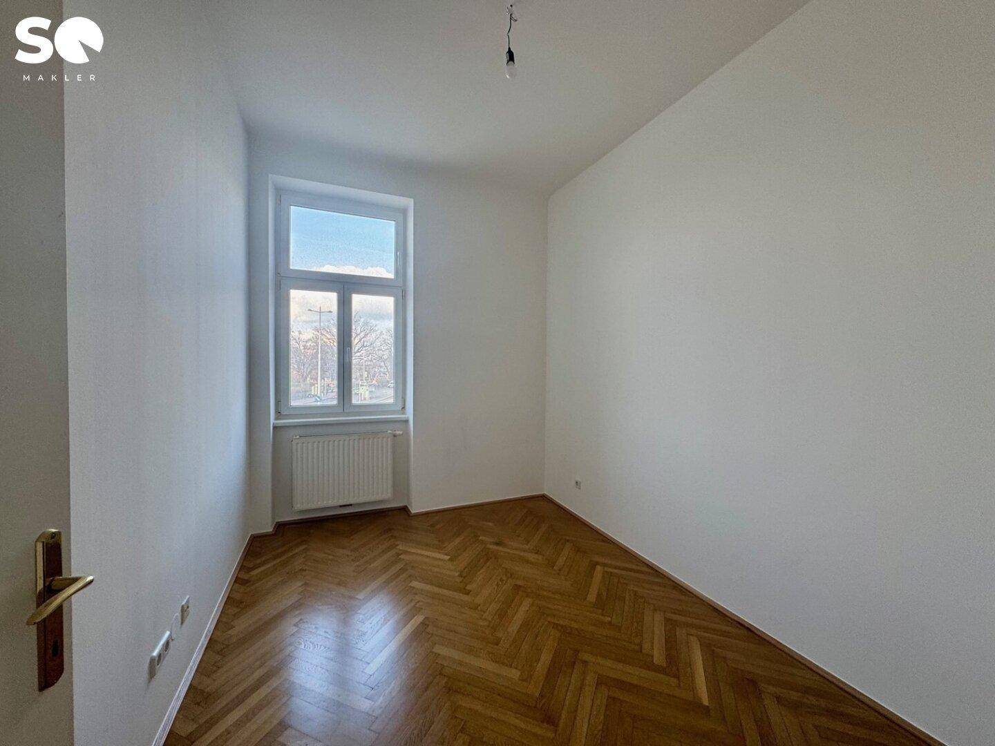 Ruhiges Zimmer mit Fischgrätparkett und einem großen Fenster für natürliche Belichtung.