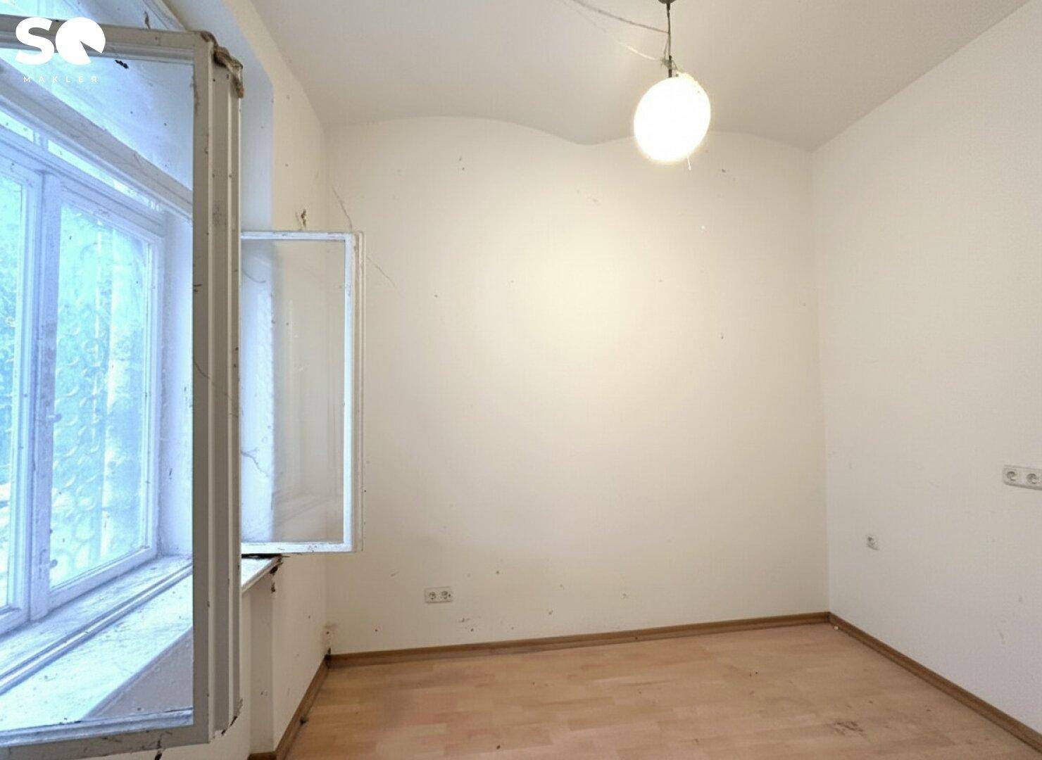 Detailansicht des geöffneten Fensters in einem leeren Raum mit Parkettboden und weißen Wänden.