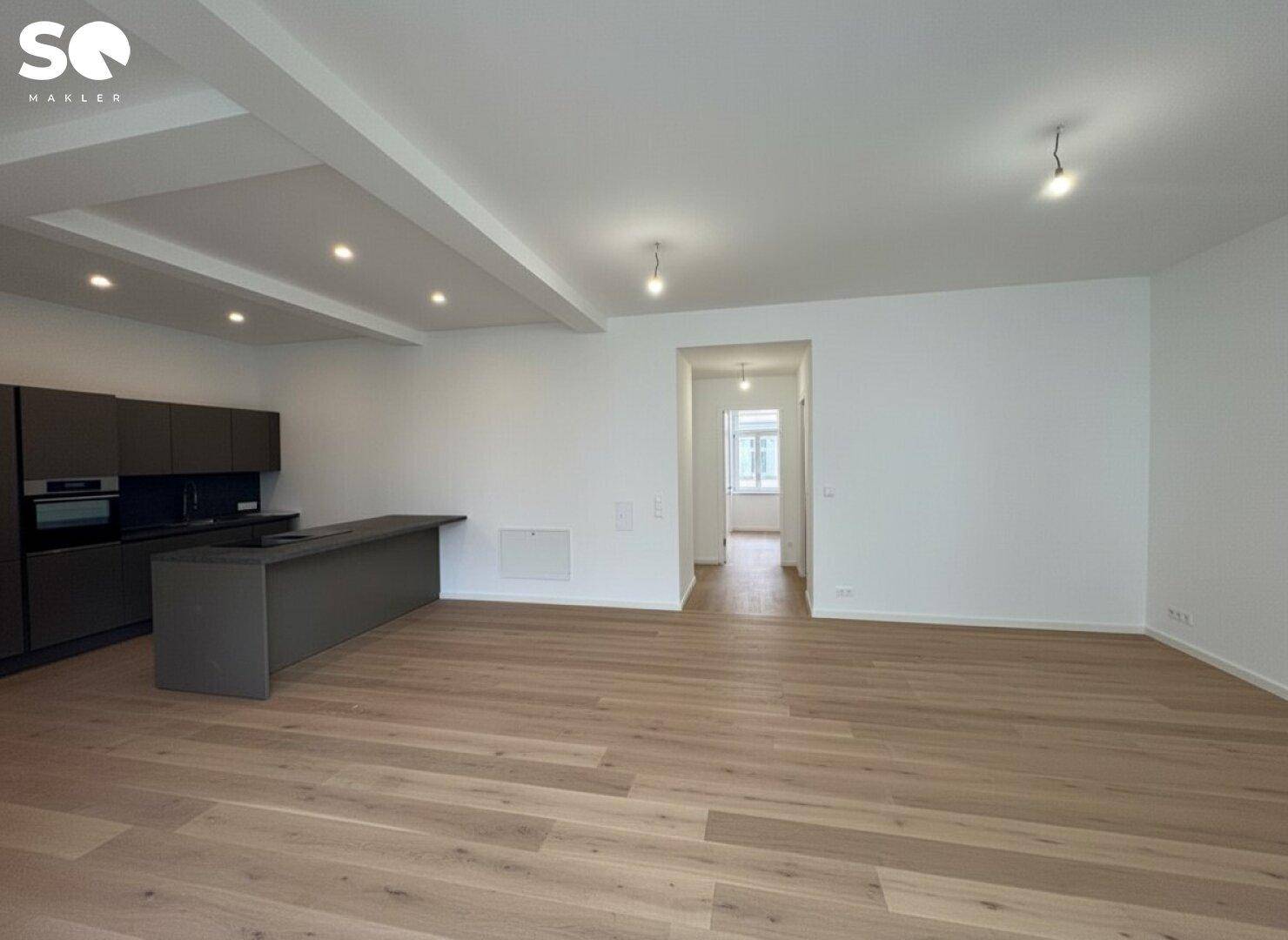 Moderner offener Wohnbereich mit integrierter Küche und Holzboden, ideal für geselliges Beisammensein.