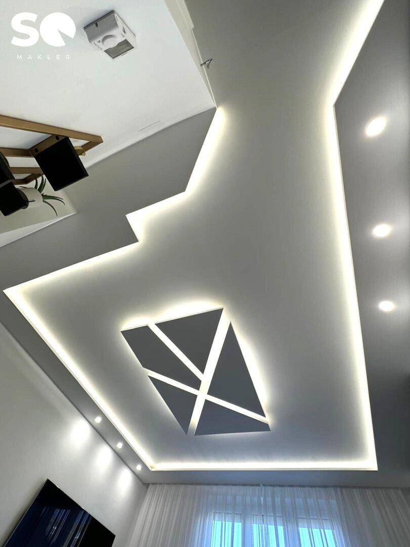 Moderne Deckenbeleuchtung mit indirektem Licht und geometrischen Mustern im Wohnbereich.