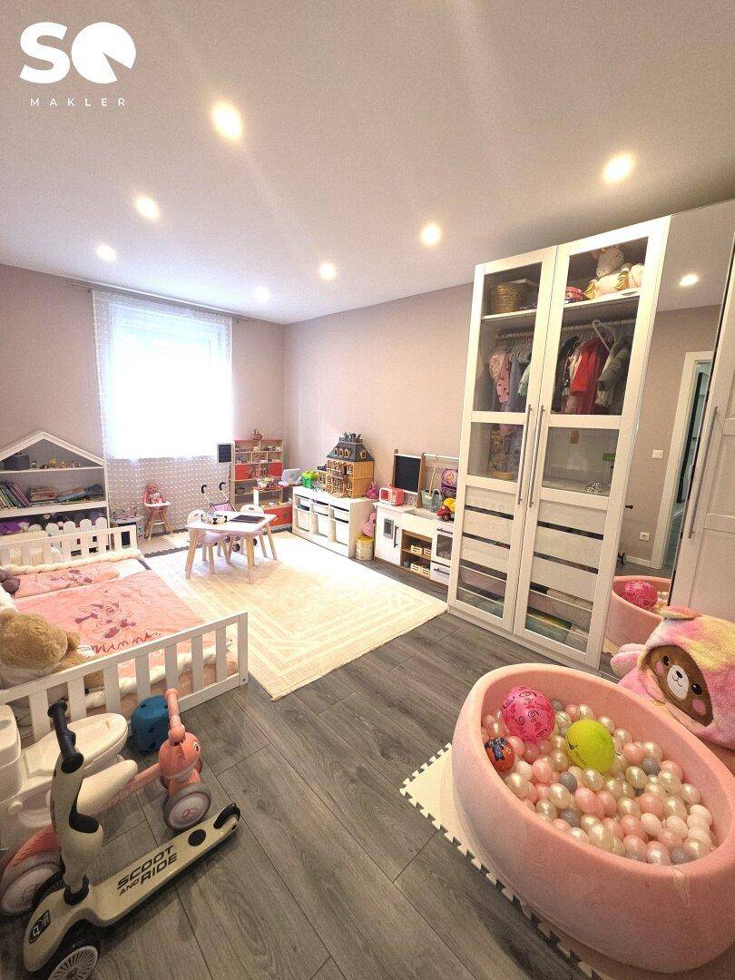 Geräumiges Kinderzimmer mit Spielbereich, Schrank und hellem Bodenbelag.