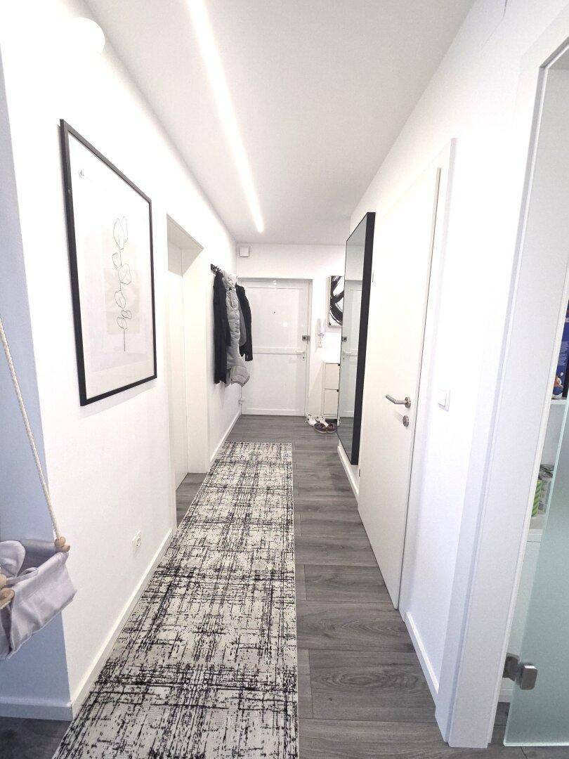Heller Flur mit modernem Bodenbelag und Garderobe, der zum Eingangsbereich führt.