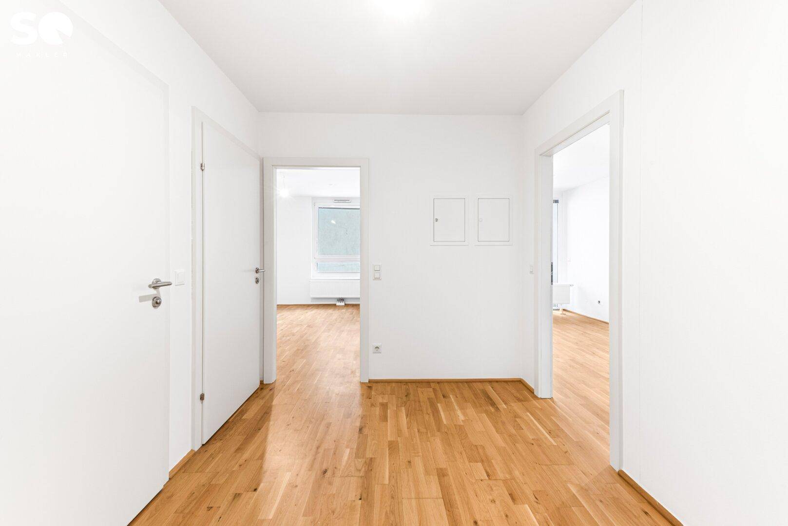 Heller Flur mit Parkettboden und Zugang zu verschiedenen Zimmern der Wohnung.