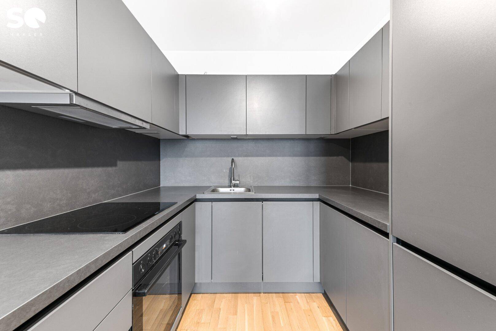 Moderne Küchenzeile in Grau mit integrierten Geräten und Induktionskochfeld.