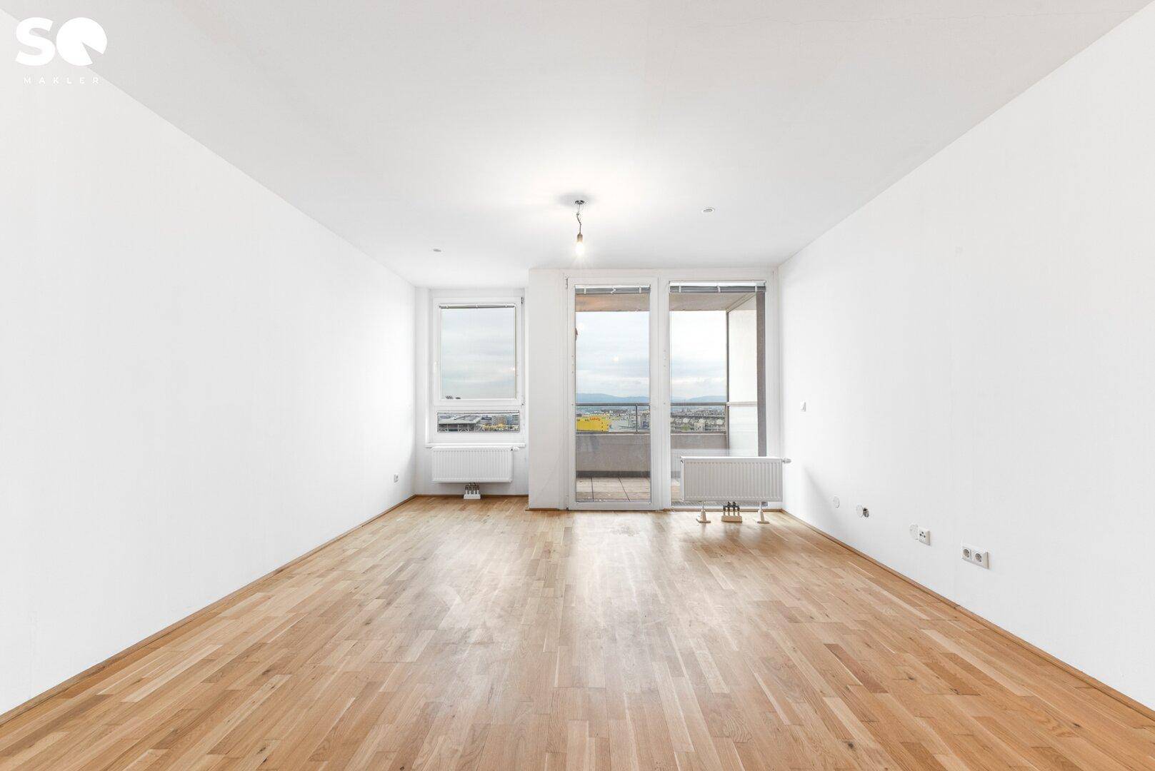 Lichtdurchflutetes Wohnzimmer mit Parkettboden und Zugang zum Balkon mit Panoramablick.