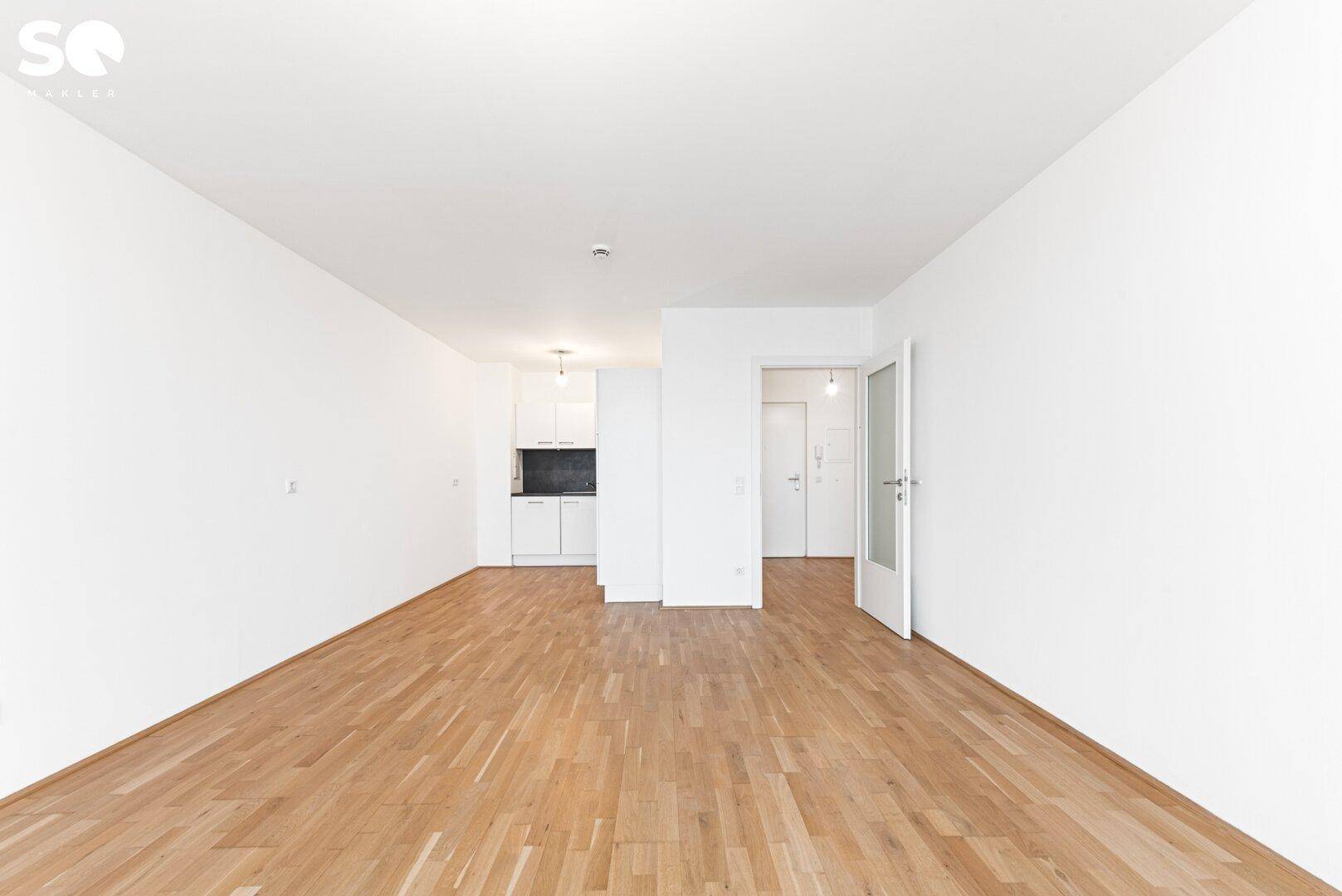 Offener Wohnbereich mit Parkettboden und integrierter Küchenzeile, ideal für modernes Wohnen.