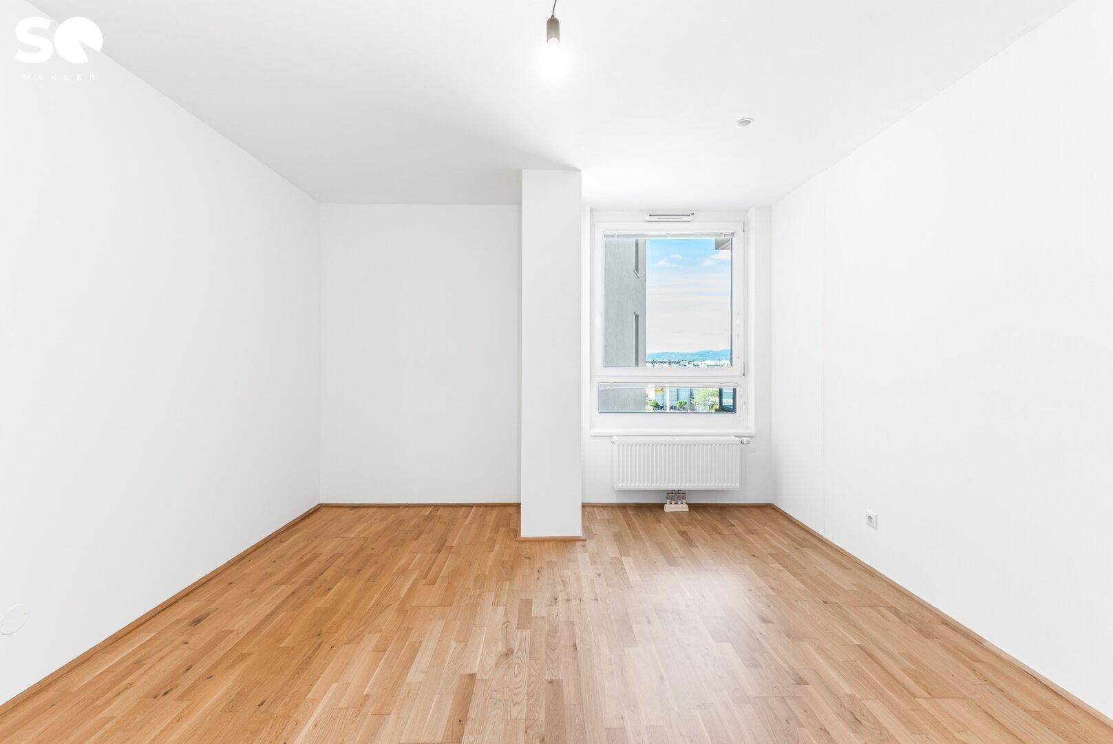 Helles Schlafzimmer mit Parkettboden und großem Fenster, das einen weiten Blick bietet.