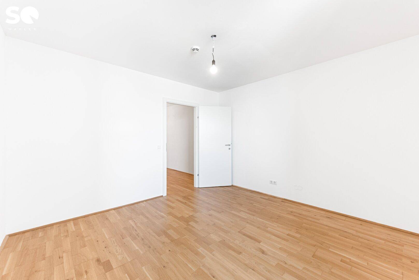 Leeres Schlafzimmer mit Parkettboden und weißen Wänden, bereit zur individuellen Gestaltung.