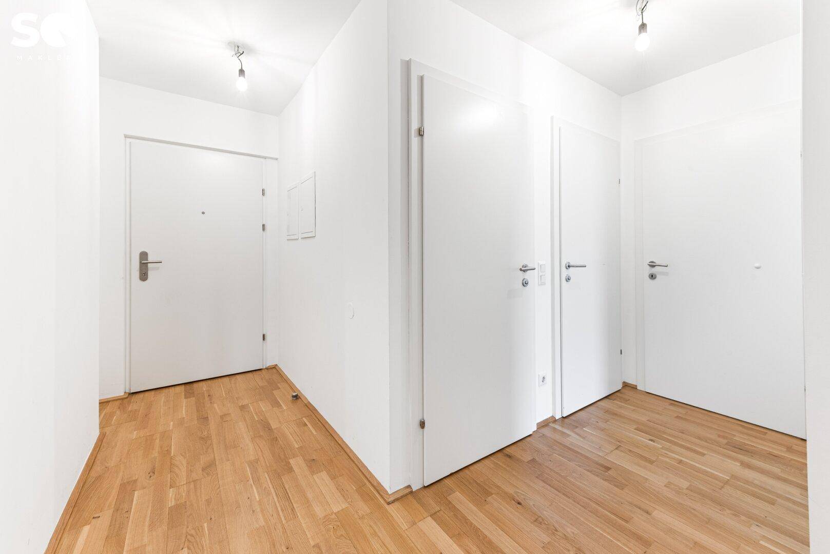 Heller Flur mit Holzboden und mehreren weißen Türen, die zu den angrenzenden Räumen führen.