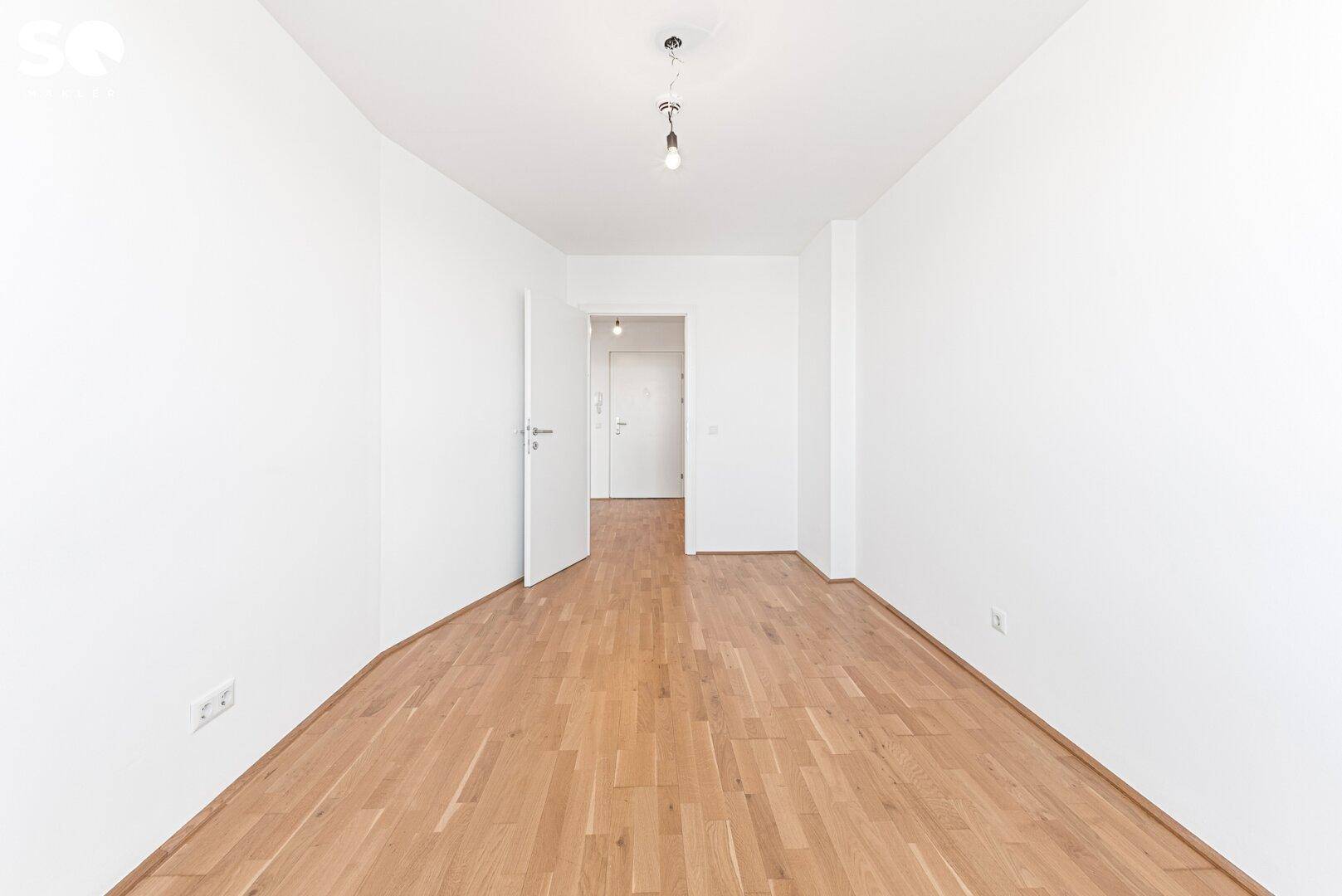 Geräumiges Zimmer mit Parkettboden und weiß gestrichenen Wänden, ideal als Schlaf- oder Arbeitszimmer.