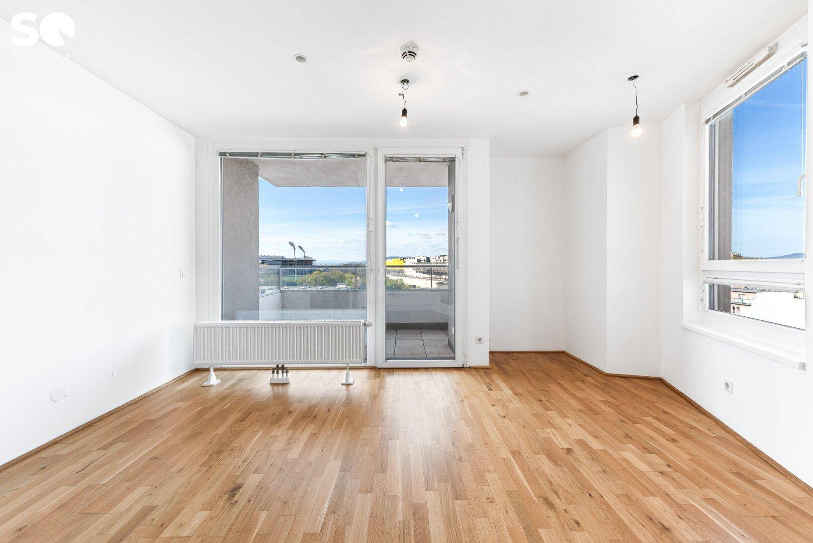 Helles Wohnzimmer mit Parkettboden und Zugang zu einem Balkon, ideal für individuelle Gestaltung.
