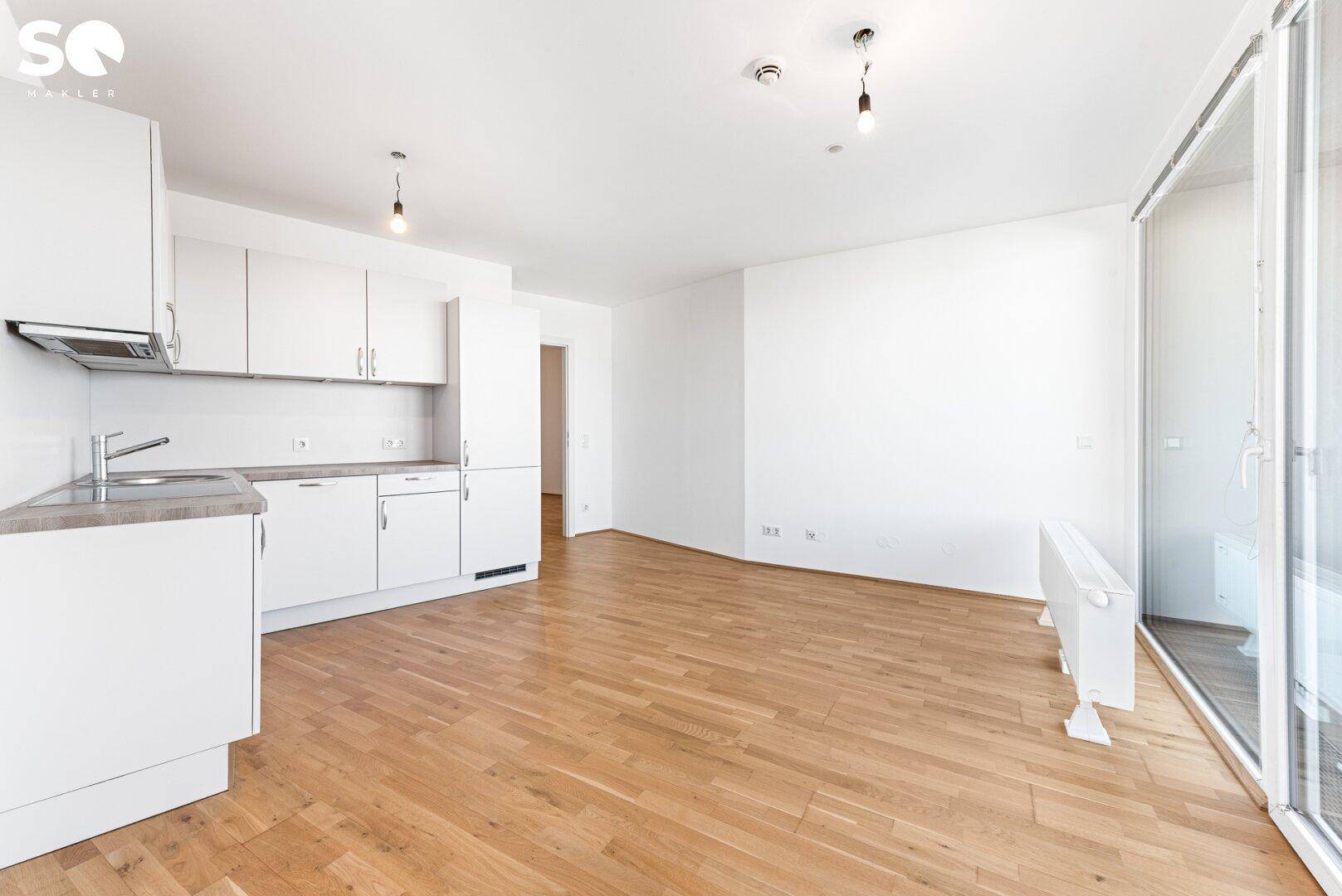 Heller Wohnbereich mit integrierter Küchenzeile und direktem Zugang zum Balkon.