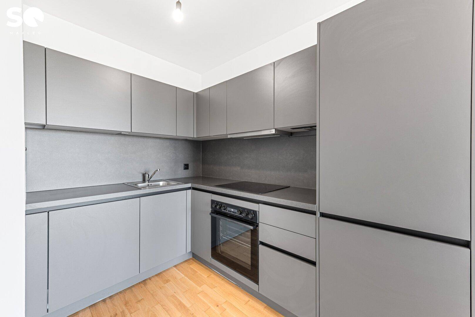 Moderne Einbauküche in Grau mit integrierten Geräten und Holzfußboden.
