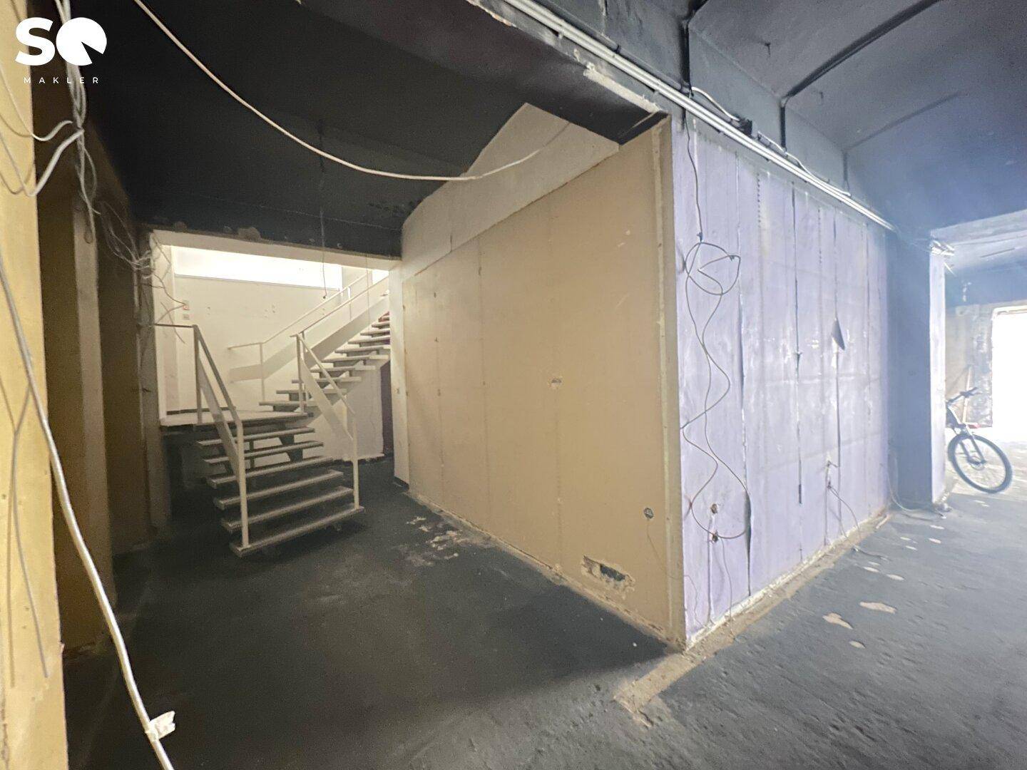 Treppenhaus in einem Geschäftsgebäude mit einfacher Metallgeländer und unfertigen Wänden, bereit für die Renovierung.
