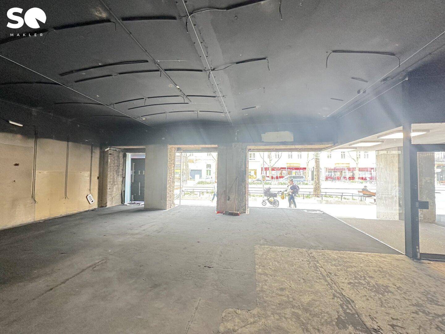 Großer, offener Geschäftsraum mit dunkler Decke und Boden, Blick auf die Straße und viel Potenzial für Gestaltung.