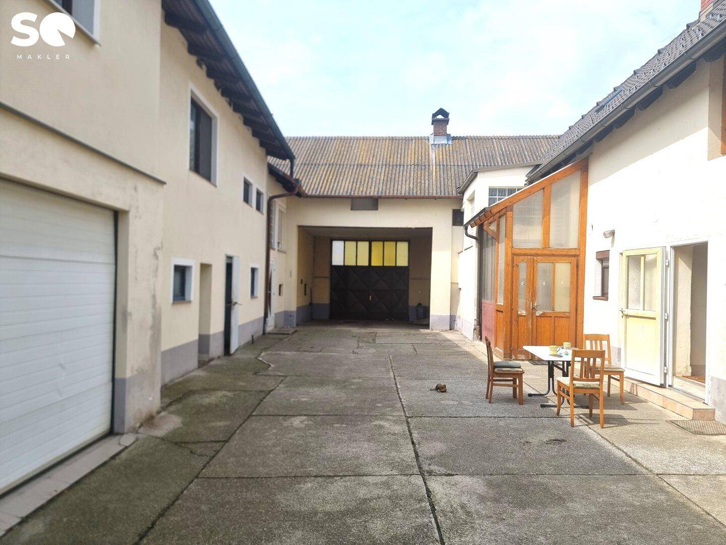 Gepflasterter Innenhof zwischen Gebäuden mit einer kleinen Sitzecke im Freien.