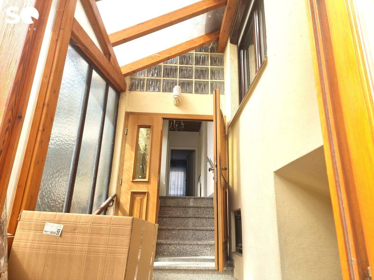 Eingangsbereich mit Holzverkleidung, Treppe und Glasbausteinen, die für natürliches Licht sorgen.