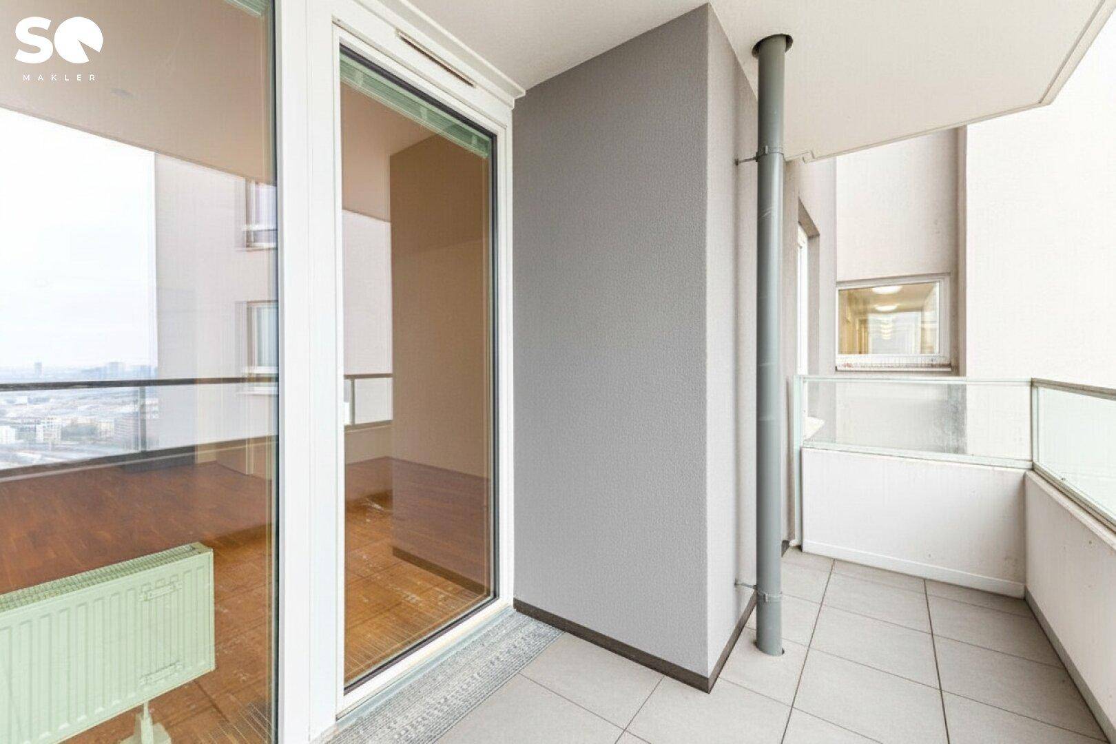 Heller Balkon mit Fliesenboden und Glasbrüstung, bietet eine weite Aussicht.