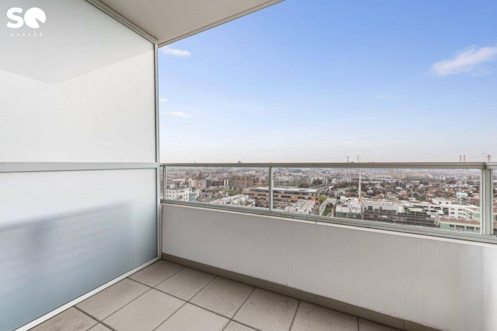 Balkon mit Fliesenboden und weitem Panoramablick über die städtische Landschaft.