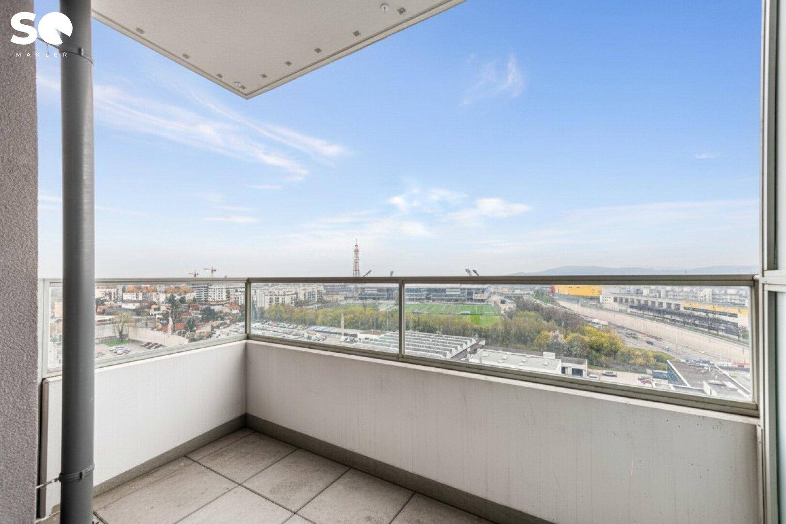 Geräumiger Balkon mit Fliesenboden und Glasbrüstung bietet einen weiten Blick über die Stadt.