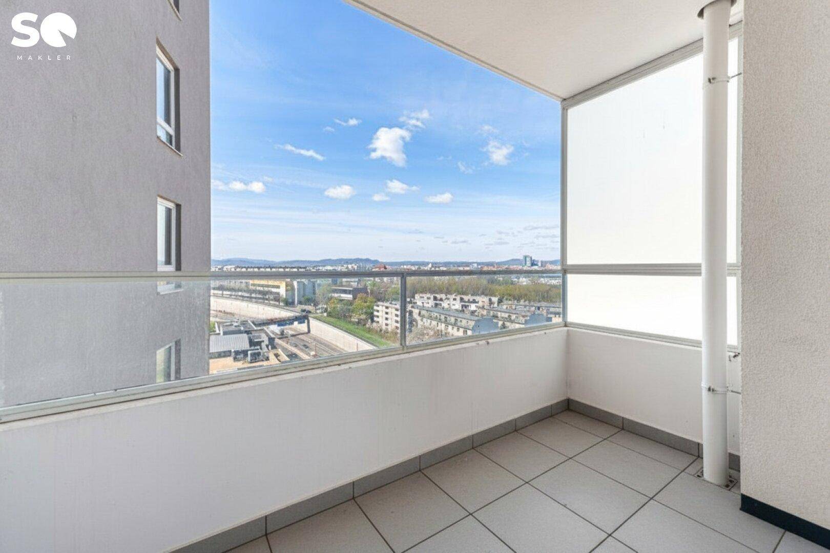 Heller Balkon mit Fliesenboden und Glasbrüstung bietet einen weiten Blick über die Stadt.