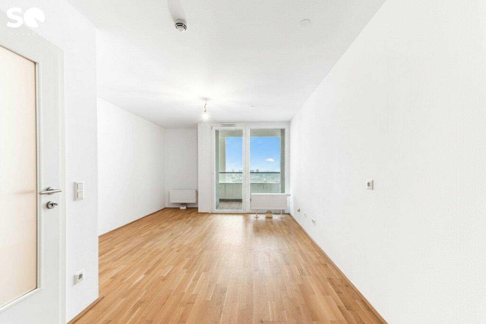 Lichtdurchfluteter Raum mit Parkettboden und Zugang zu einem Balkon, bereit zur Einrichtung.