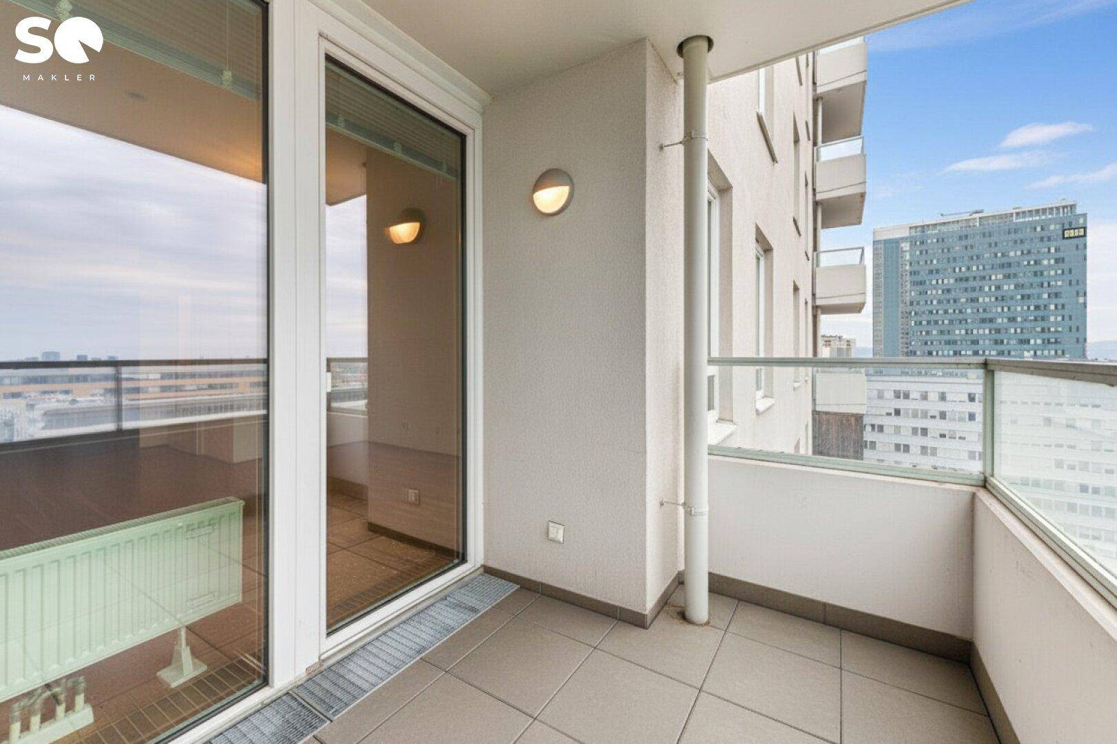 Heller Balkon mit Fliesenboden und Blick auf die umliegenden Gebäude und die Stadt.