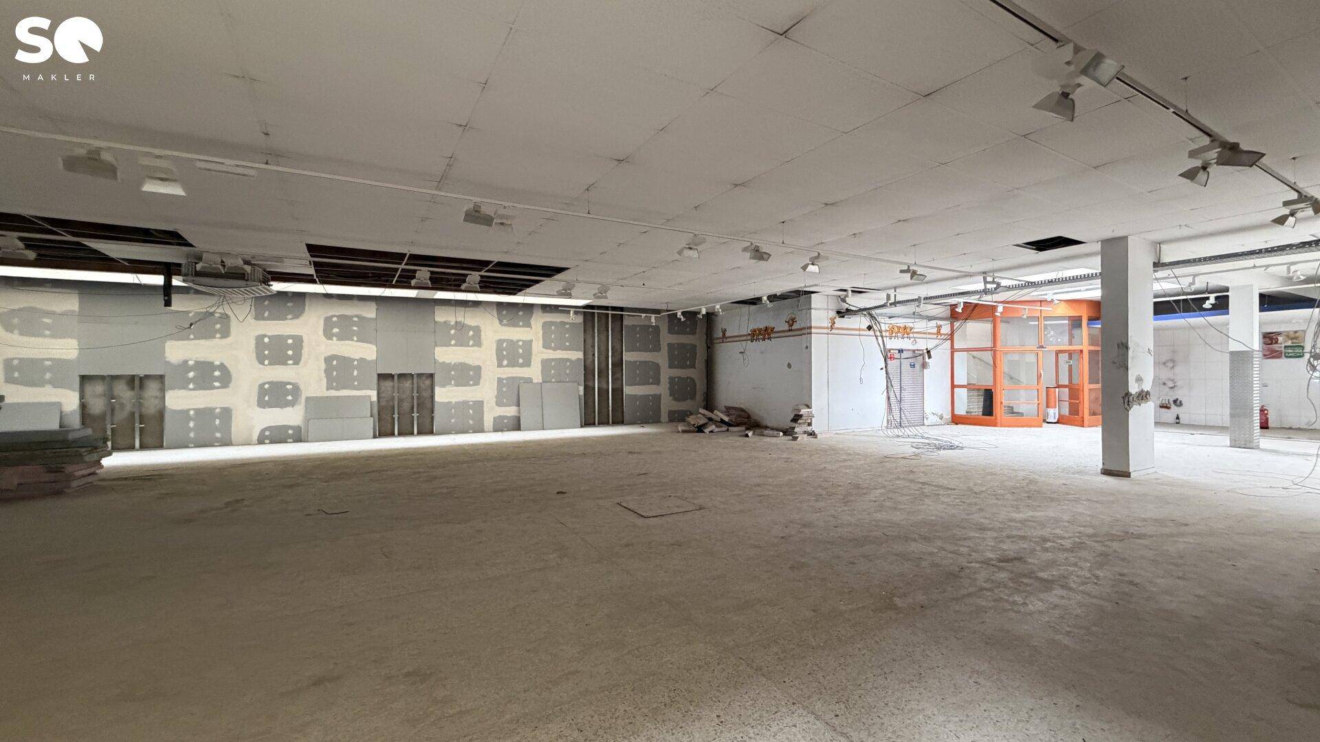 Geräumiger Gewerberaum in Renovierung mit Oberlichtern und teilweise verputzten Wänden, bereit für den Ausbau.