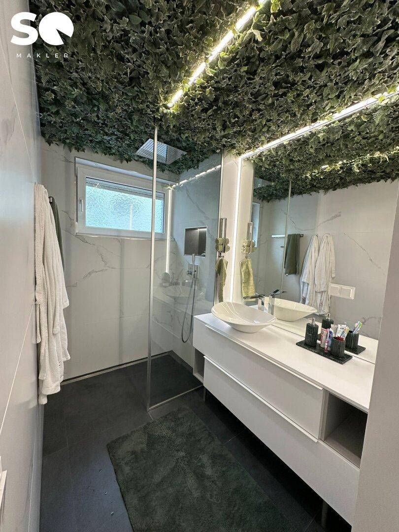 Modernes Badezimmer mit begehbarer Dusche, Doppelwaschbecken und grüner Deckenverkleidung.
