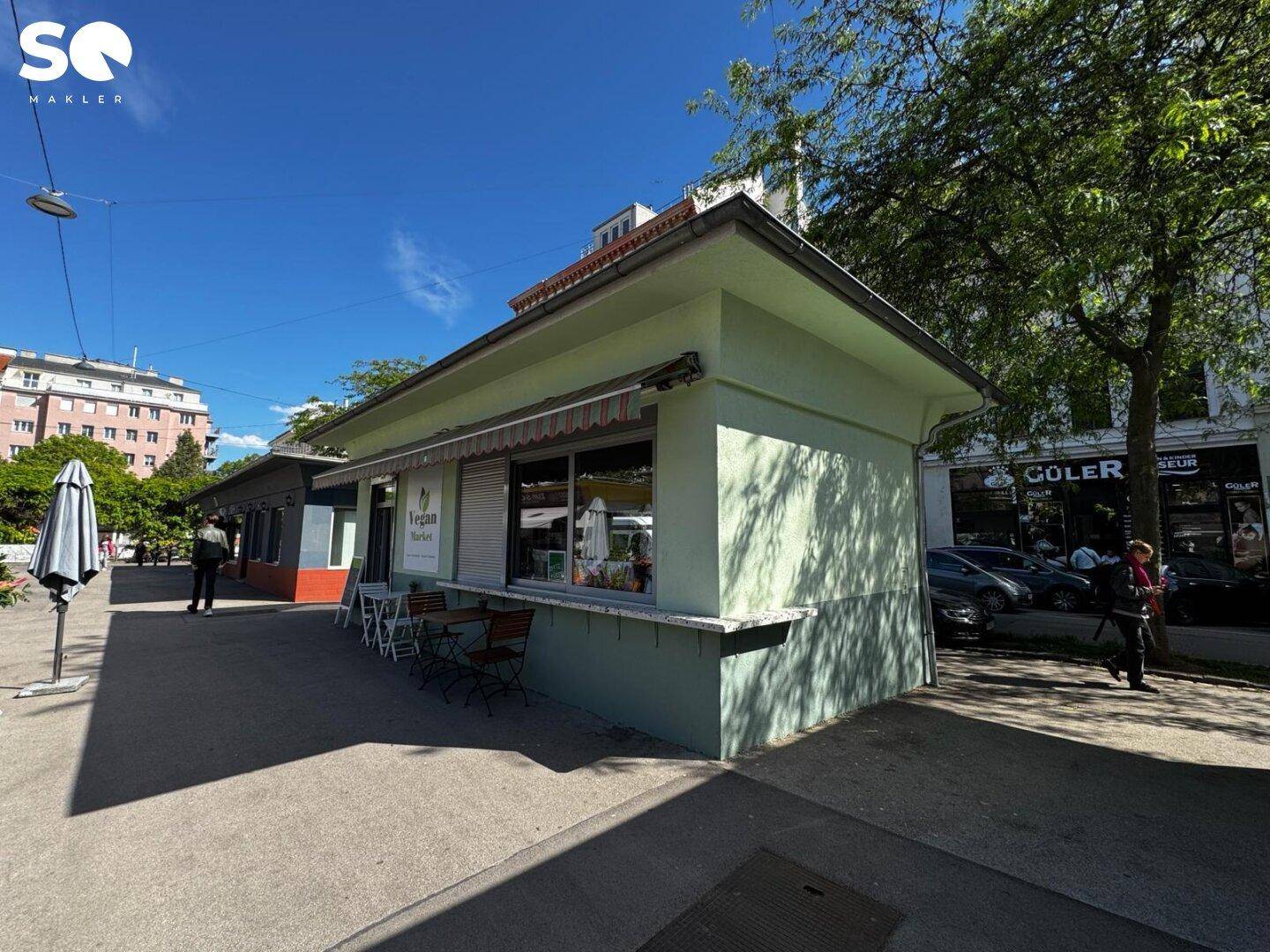 Weitwinkelaufnahme des Gebäudes und seiner Umgebung, zeigt die Straße, Bäume und angrenzende Gebäude.