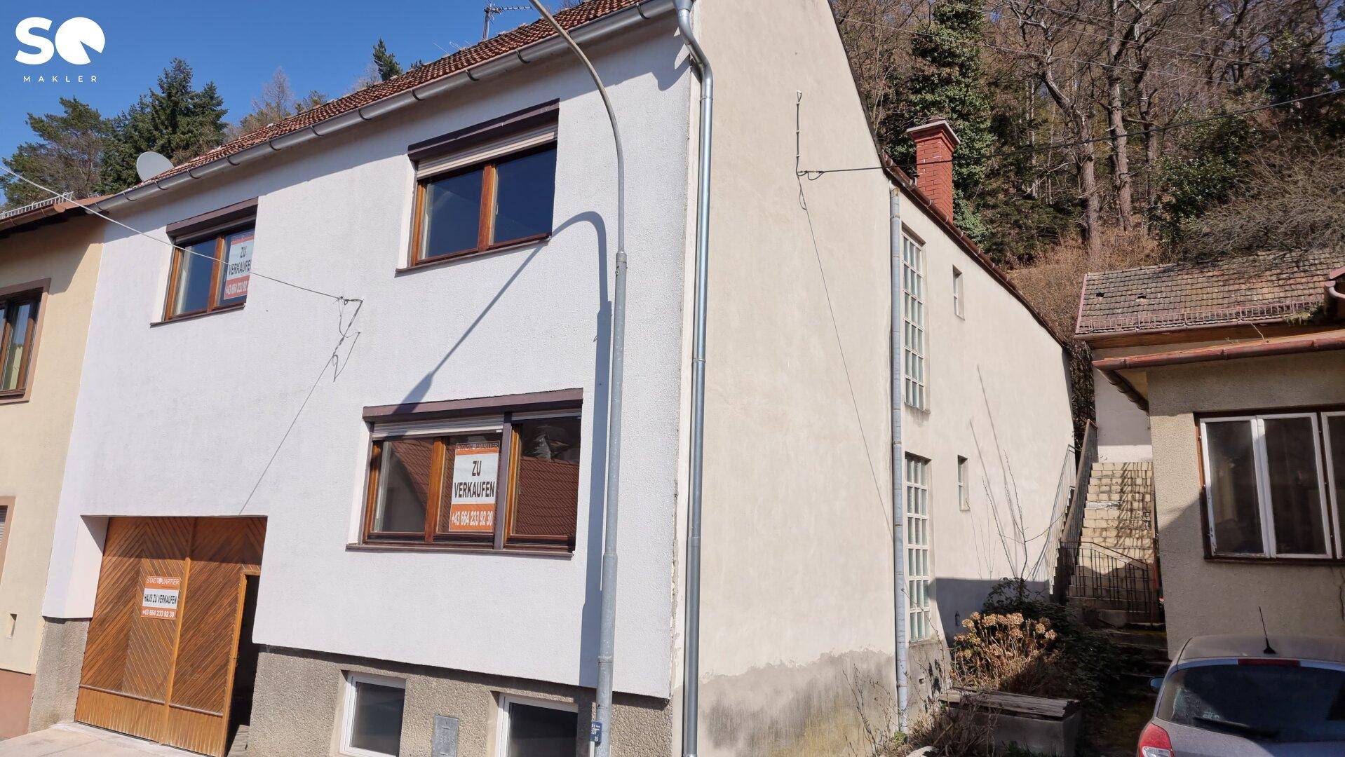 Seitenansicht des Hauses mit weißer Fassade und angrenzendem Gebäude.