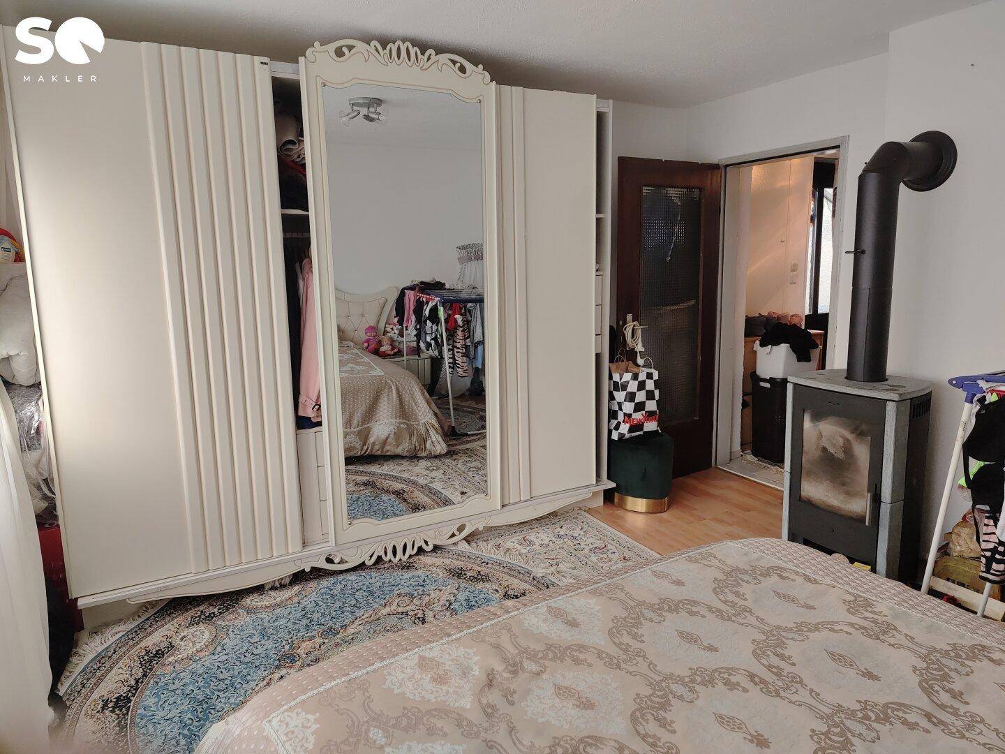Schlafzimmer mit großem Spiegelschrank und einem Holzofen.