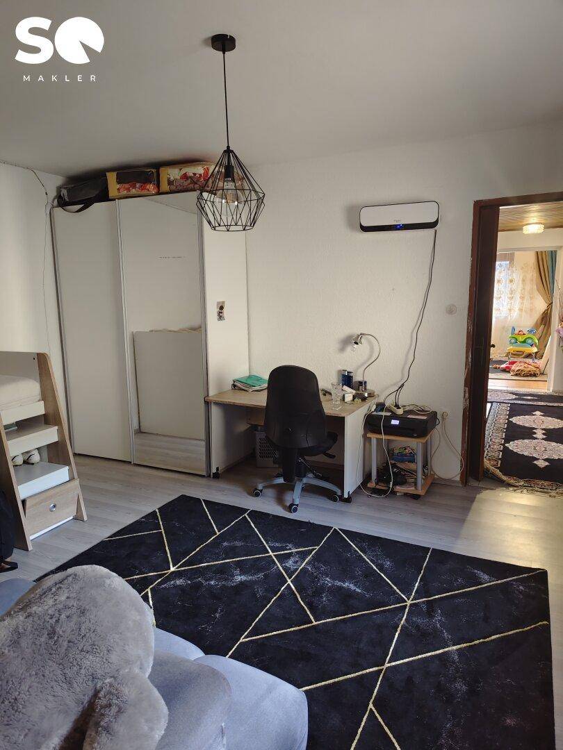 Schlafzimmer mit Schreibtisch, Bürostuhl und großem Kleiderschrank.