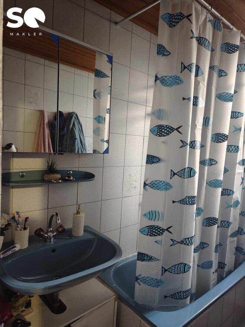Badezimmer mit blauem Waschbecken, Spiegelschrank und Badewanne mit Duschvorhang.