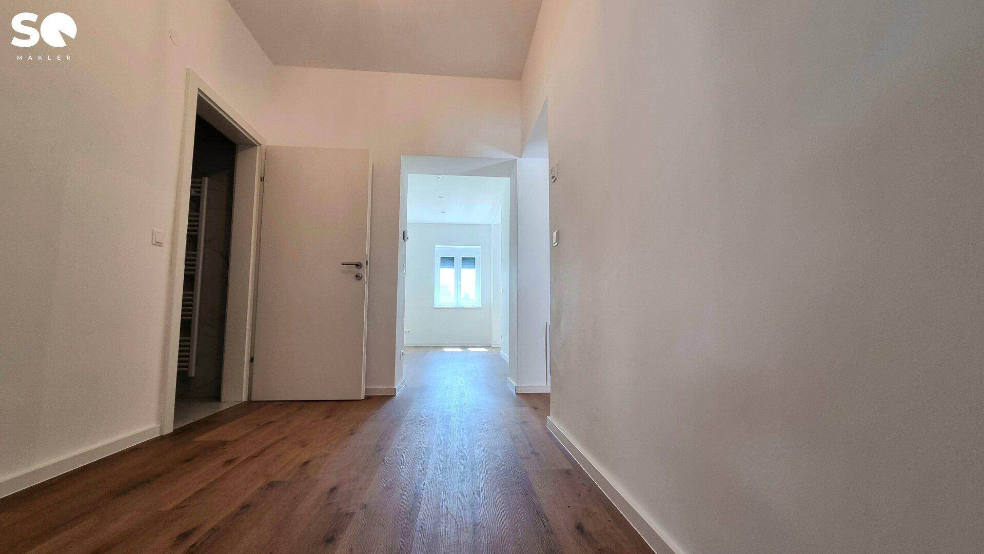 Langer Flur mit Laminatboden und Türen, die zu verschiedenen Räumen führen.