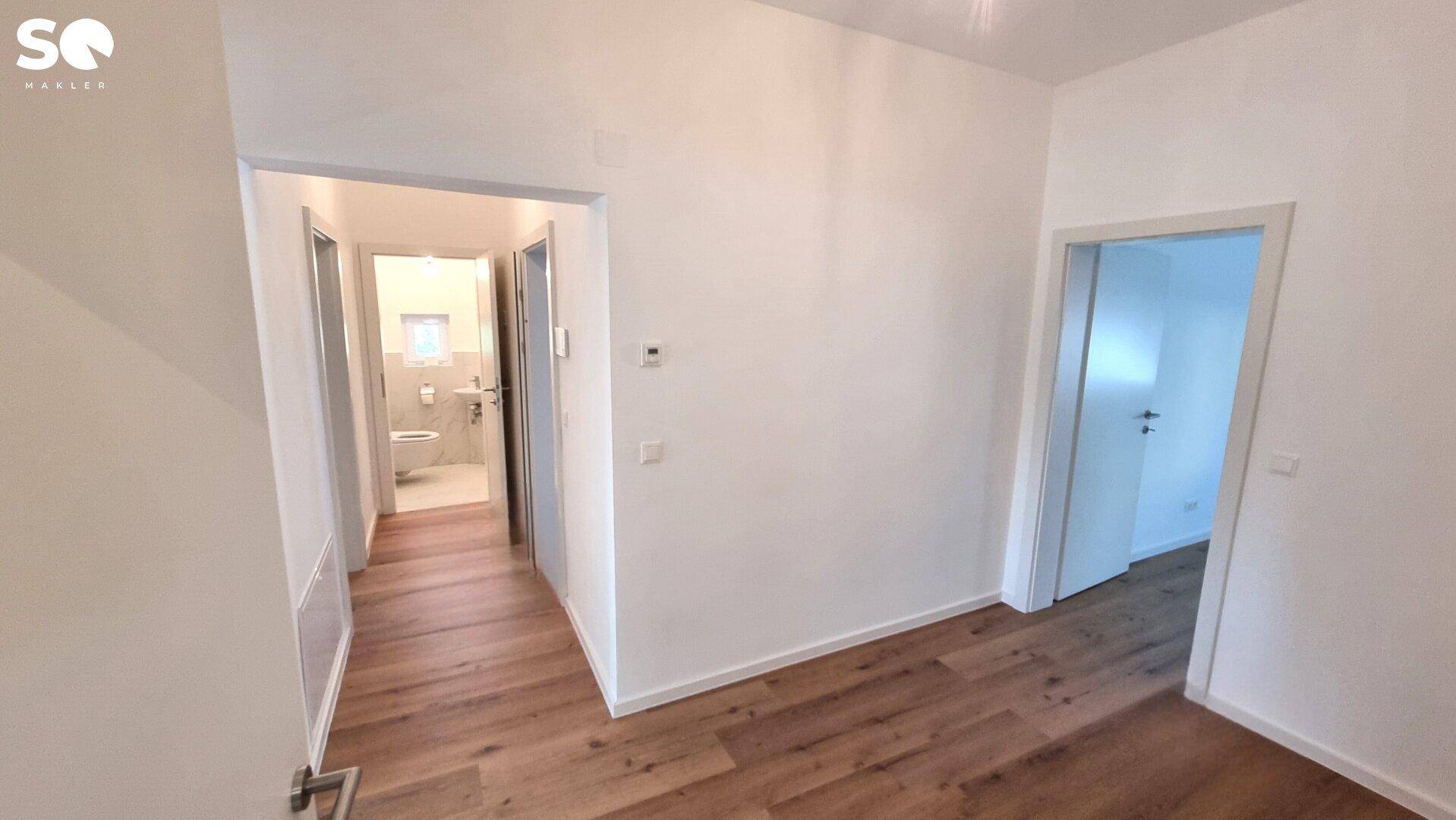 Geräumiger Flur mit Laminatboden und Zugang zu mehreren Zimmern und einem Bad.