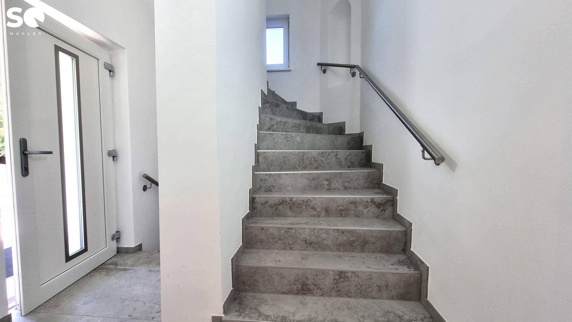 Treppenhaus mit Steinstufen und Handlauf, das zu den oberen Etagen führt.