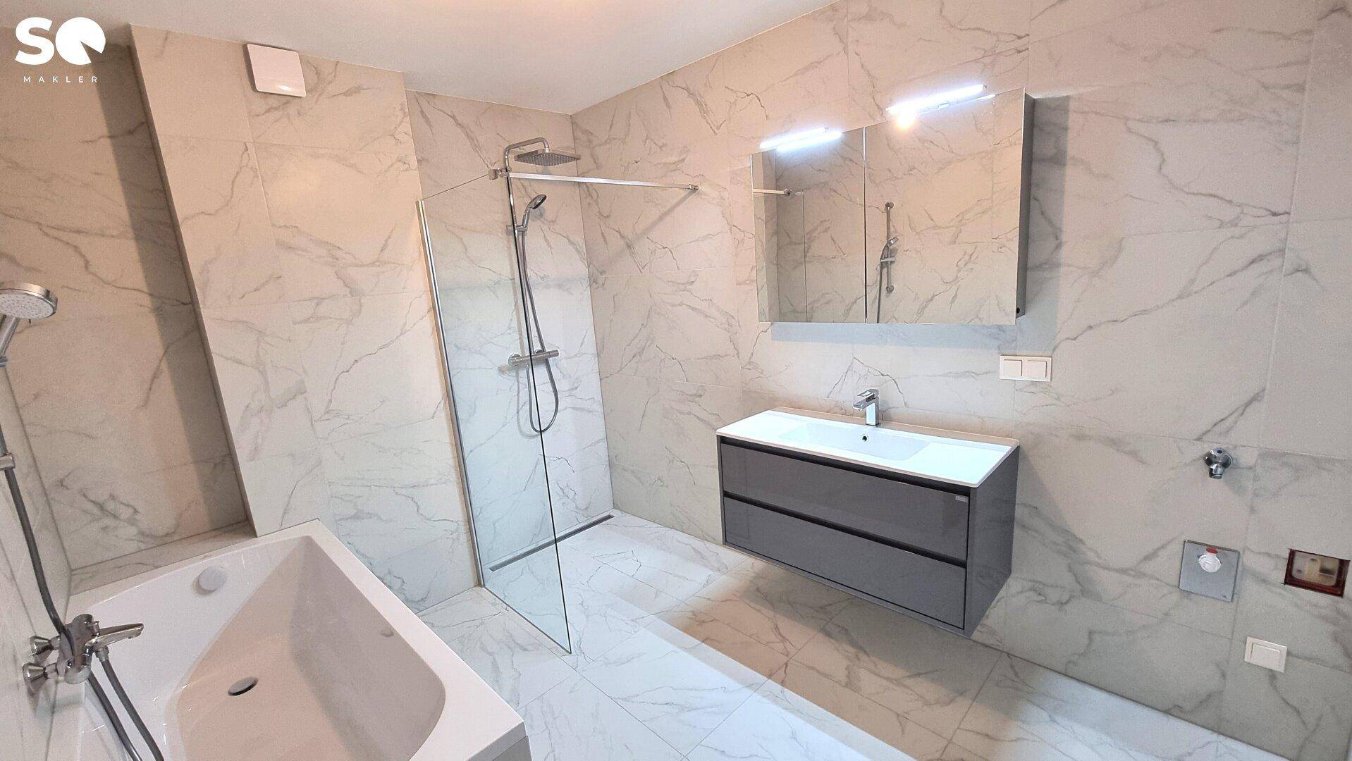 Modernes Badezimmer mit Badewanne, ebenerdiger Dusche und Waschtisch mit Spiegelschrank.